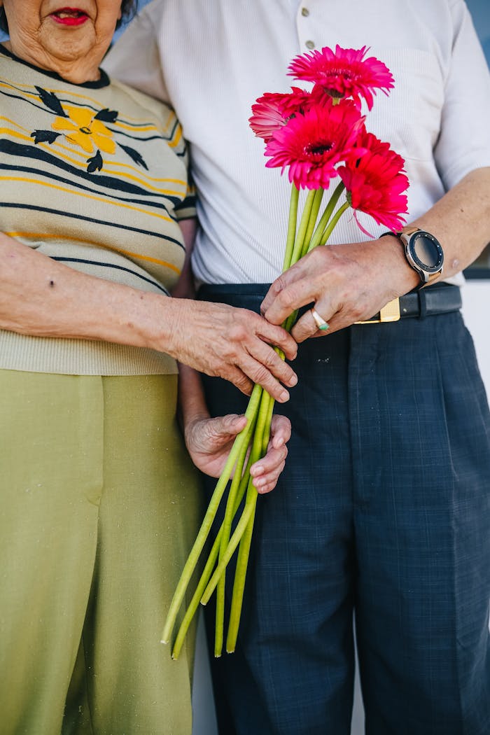 A close-up of an elderly couple exchanging red flowers, symbolizing love and togetherness.